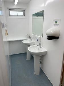 a white bathroom with two sinks and a mirror at Cow Close Camping Pods in Leyburn