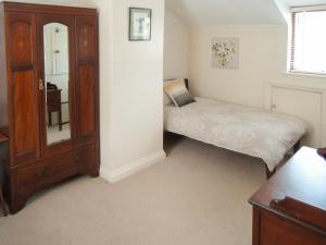 a small bedroom with a bed and a cabinet at Florin Cottage in Lerryn