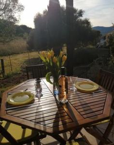 uma mesa de madeira com dois pratos e um vaso de flores em MAISON ALBA ROSSA 55 em Serra-di-Ferro