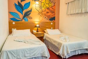 two beds in a room with a painting on the wall at Los Lagos Resort Hotel in Capiatá