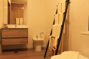 a bathroom with a toilet and a sink and a towel rack at Casa do Centro in Pessegueiro +14 photos