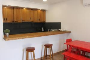 a kitchen with wooden cabinets and a red table and stools at Casa do Centro in Pessegueiro