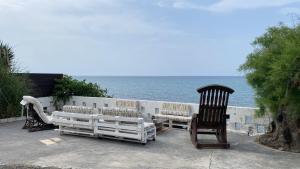 Ayyorgi的住宿－High By The Beach House in Girne，海边的长凳和两把椅子