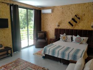 um quarto com uma cama, uma cadeira e uma janela em La Perle de l'Ourika em Ourika