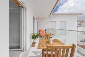 een kamer met een houten tafel en stoelen op een balkon bij Apartamento Figueiras in Nazaré