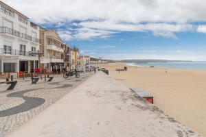een zandstrand met gebouwen en mensen die erop lopen bij Apartamento Figueiras in Nazaré