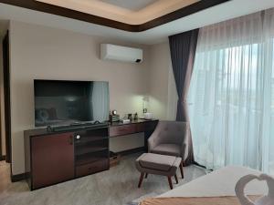 a hotel room with a tv and a chair and a bedroom at One Euphoria walking st Condotel Angeles city in Angeles