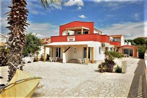 a red and white house with a palm tree in front of it at Graf-Apartments-Vir-Zadar in Vir