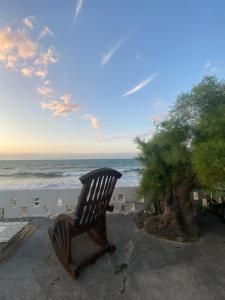 High By The Beach House in Girne في Ayyorgi: مقعد خشبي بجانب المحيط