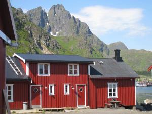 a red house with a mountain in the background at Naustplassen Rorbuer in Ballstad