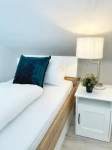 ein Bett mit einem blauen Kissen und einem Nachttisch mit einer Lampe in der Unterkunft Pension Zur Mühle in Grifte