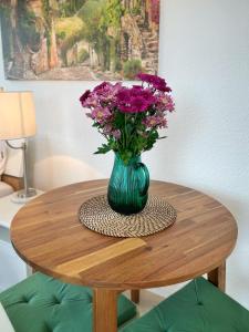 eine grüne Vase mit lila Blumen auf einem Tisch in der Unterkunft Pension Zur Mühle in Grifte