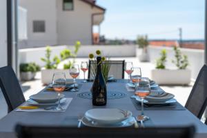 a table with glasses and a bottle of wine on it at Apartmani Ville Vengo in Trogir