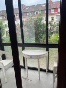 une table et des chaises blanches devant une fenêtre dans l'établissement Holiday Home, à Brême