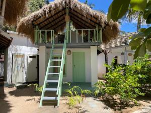 a ladder in front of a house with a thatch roof at Banana Surf House in Arugam Bay