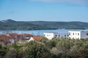 a group of white buildings on a hill next to a lake at Apartments Sandra in Turanj