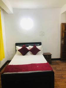 sypialnia z łóżkiem z białymi i czerwonymi poduszkami w obiekcie Darjeeling Homestay w mieście Dardżyling