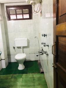 łazienka z toaletą i zieloną podłogą w obiekcie Darjeeling Homestay w mieście Dardżyling