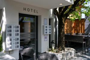 a hotel with chairs and a tree on a sidewalk at Aktivhotel Wildschütz in Altmünster
