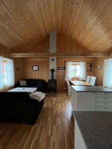 a living room with a black couch and wooden ceiling at Naustplassen Rorbuer in Ballstad