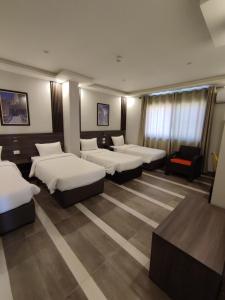 een hotelkamer met 4 bedden en een stoel bij Black Iris Hotel II in Madaba