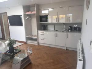 a kitchen with white cabinets and a glass table at Dafarn Newydd Lodge in Llangefni