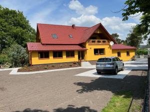 een geel huis met een rood dak op een parkeerplaats bij U Marků in Staré Splavy