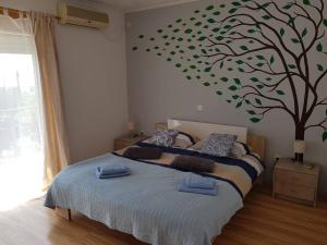 a bedroom with a bed with a tree on the wall at Mediterranean ocean view 4star appartment in Villa in Rijeka