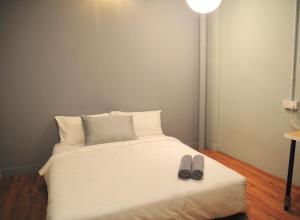Una cama con dos pares de zapatos encima en GRAYHAUS SOHO Ipoh, en Ipoh