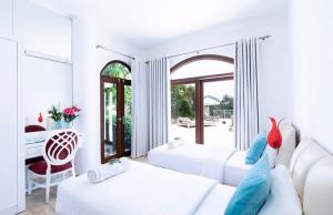a white room with two beds and a table at The Korsan Kuzey in Kas