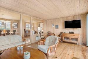 sala de estar con sofá y TV en Lovely Holiday Home On The Beach At Trres, en Otterup