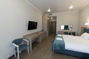 a hotel room with a bed and a desk and a tv at Апсилиа in Sukhum