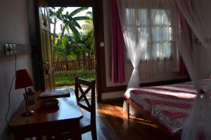 a bedroom with a bed and a table and a window at Hotel Ambalakely in Ambalakely