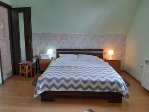 a large bed in a bedroom with two tables and two lamps at Vila Coca in Predeal