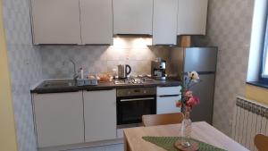 a kitchen with white cabinets and a table with a vase of flowers at Iva in Zadar