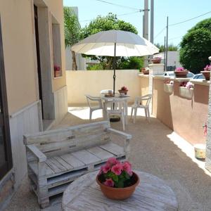 eine Holzbank mit einem Tisch und einem Regenschirm in der Unterkunft Casa Salento Maria in Marina di Mancaversa