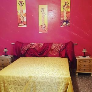 une chambre avec un lit et un mur rose avec des photos dans l'établissement Casa Salento Maria, à Marina di Mancaversa