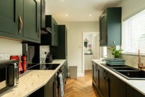 a kitchen with green cabinets and a counter top at Ellistown Retreat in Hugglescote