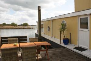 una terrazza in legno con tavolo e sedie su una barca di Ecostay de IJsvogel a Kampen