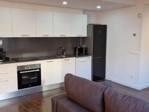 a kitchen with white cabinets and a couch in a room at Espectacular piso nuevo con piscina in Platja  d'Aro