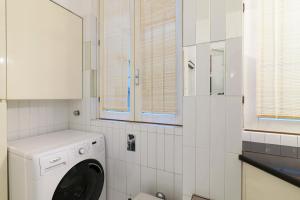 a white washing machine in a white tiled bathroom at Elegant Terrace Suite in Milan