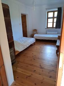 a room with two beds and a wooden floor at Gospodarstwo Agro-Turystyczne Kuty in Pozezdrze