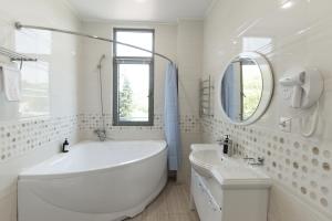 a white bathroom with a large tub and a sink at Апсилиа in Sukhum