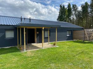 uma casa azul com um alpendre e um quintal em De Heide em Odoorn