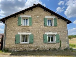 una vecchia casa di mattoni con finestre con persiane verdi di The charming private Farmhouse at La Grenouillére a Puyréaux