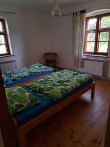 two beds sitting in a room with wooden floors at Gospodarstwo Agro-Turystyczne Kuty in Pozezdrze
