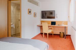 a bedroom with a bed and a desk and a television at Maiers Johanniterbad Ringhotel Rottweil in Rottweil +44 photos