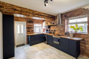 a kitchen with blue cabinets and a brick wall at Exclusive House with Canadian Hot Tub in Great Yarmouth