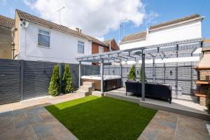 a garden with a pergola and grass at Exclusive House with Canadian Hot Tub in Great Yarmouth