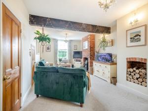 uma sala de estar com um sofá verde e uma lareira em Bells Cottage em Wrentham